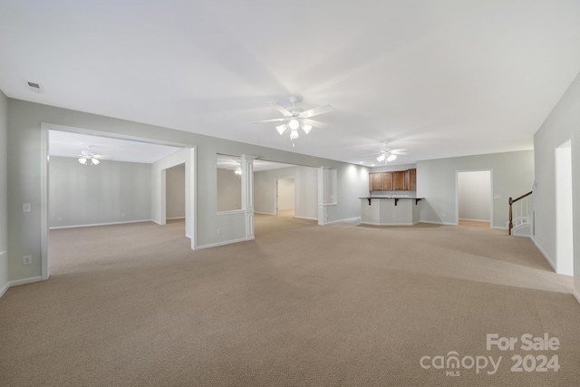 unfurnished living room featuring light colored carpet and ceiling fan