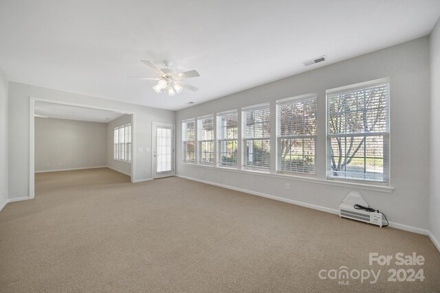 spare room with light colored carpet, a wealth of natural light, and ceiling fan