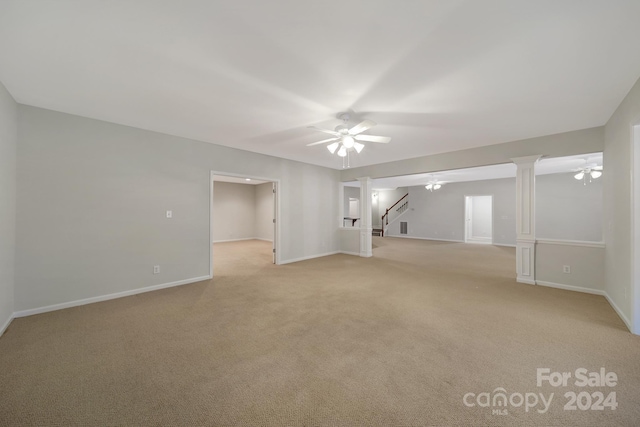 unfurnished room featuring light colored carpet, ceiling fan, and decorative columns