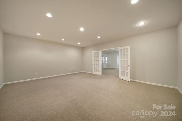 spare room featuring light carpet and french doors