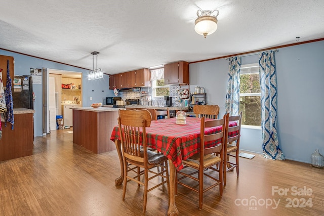 dining room with light hardwood / wood-style floors, a textured ceiling, and ornamental molding