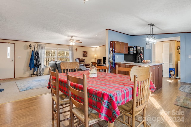 dining area with ceiling fan with notable chandelier, a textured ceiling, and light wood-type flooring