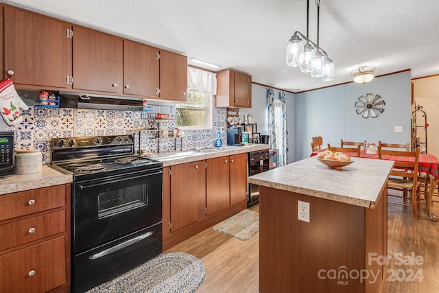 kitchen featuring a center island, black appliances, hanging light fixtures, light wood-type flooring, and tasteful backsplash