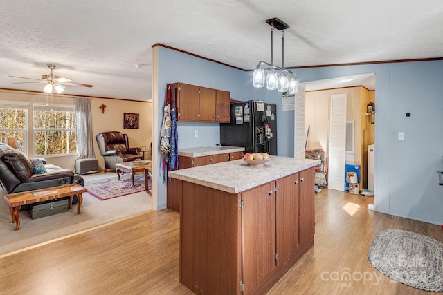 kitchen with black refrigerator with ice dispenser, light hardwood / wood-style flooring, crown molding, and a textured ceiling