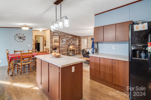 kitchen with light wood-type flooring, black fridge with ice dispenser, crown molding, wooden walls, and decorative light fixtures