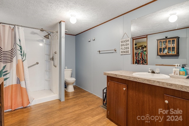 bathroom featuring hardwood / wood-style floors, a textured ceiling, toilet, vanity, and a shower with shower curtain