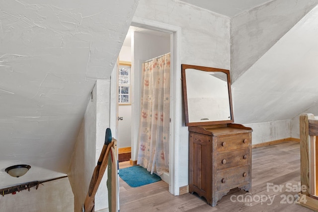 stairs featuring hardwood / wood-style flooring and lofted ceiling