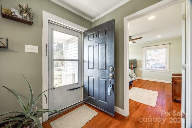 foyer entrance with crown molding, ceiling fan, and dark wood-type flooring