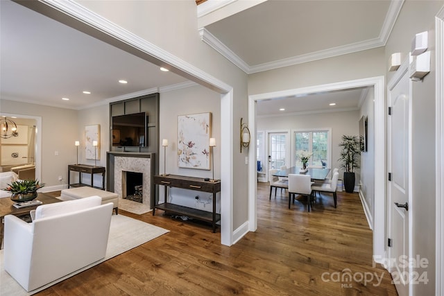 living room with a high end fireplace, crown molding, dark wood-type flooring, and a notable chandelier