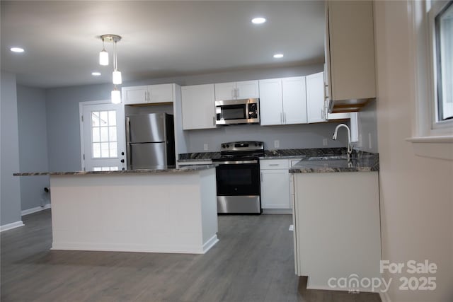 kitchen with dark wood-type flooring, white cabinetry, hanging light fixtures, stainless steel appliances, and a center island