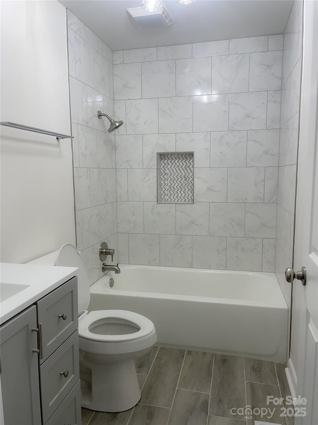 full bathroom with tiled shower / bath, vanity, and toilet