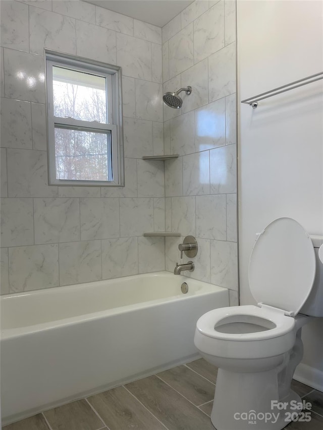 bathroom featuring tiled shower / bath and toilet