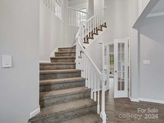 stairs with hardwood / wood-style floors, french doors, plenty of natural light, and crown molding