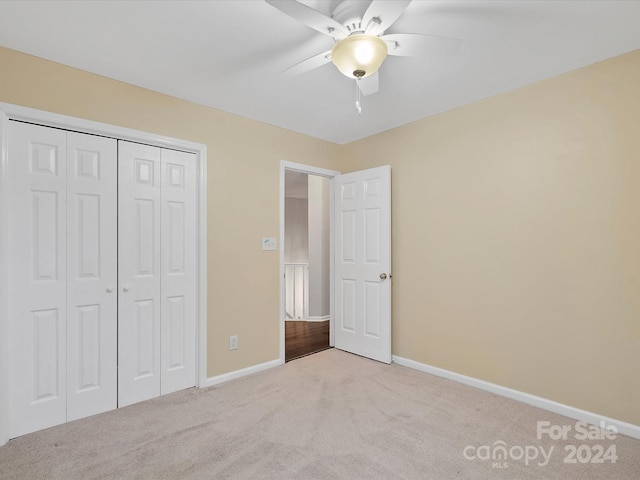 unfurnished bedroom featuring a closet, light colored carpet, and ceiling fan