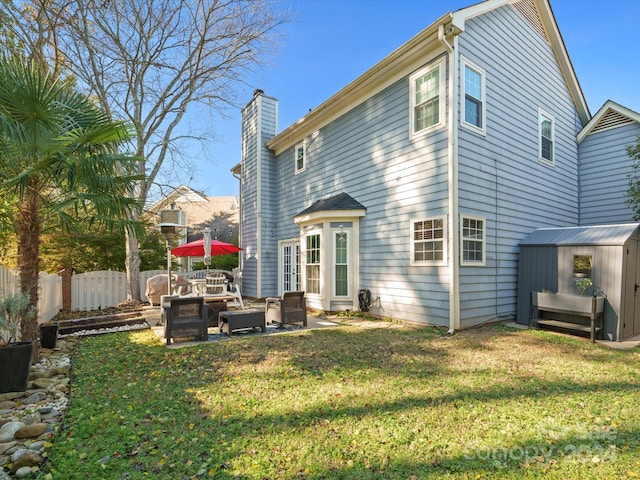 back of house featuring a yard, an outdoor living space, a shed, and a patio