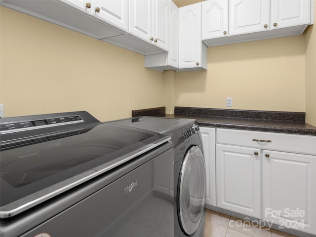 clothes washing area with cabinets, independent washer and dryer, and light tile patterned floors