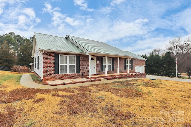 single story home featuring covered porch, a front yard, and a garage