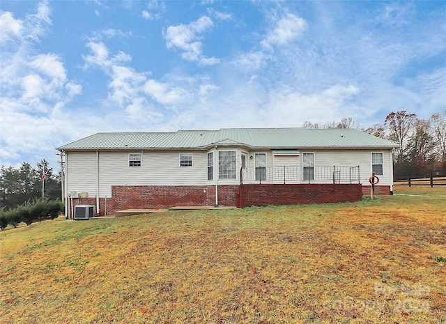 back of house with cooling unit and a lawn