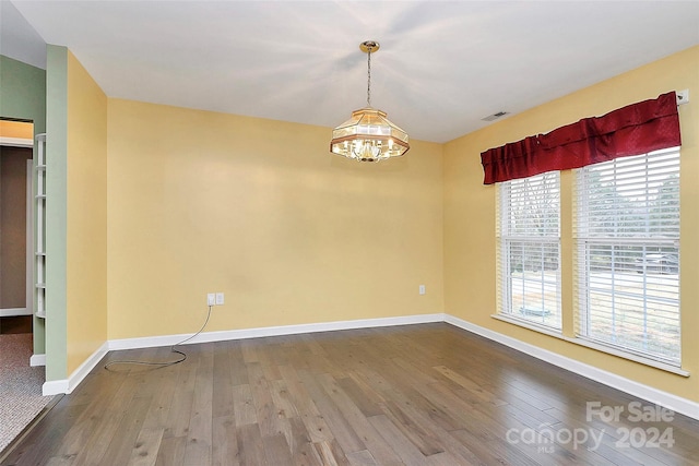 spare room featuring hardwood / wood-style floors and a notable chandelier