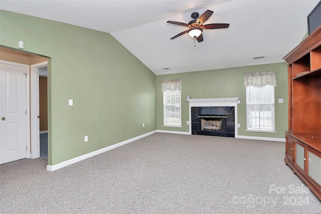 unfurnished living room with plenty of natural light, vaulted ceiling, carpet floors, and a tiled fireplace