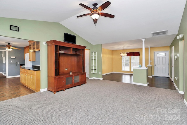 unfurnished living room featuring ceiling fan, dark carpet, ornate columns, and vaulted ceiling