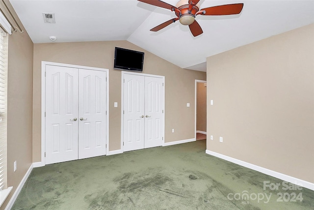 unfurnished bedroom featuring vaulted ceiling, ceiling fan, dark carpet, and two closets