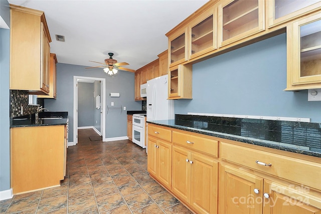 kitchen featuring white appliances, dark stone counters, sink, ceiling fan, and tasteful backsplash