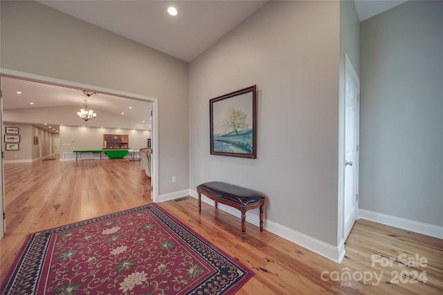 hallway featuring a notable chandelier, vaulted ceiling, and hardwood / wood-style flooring