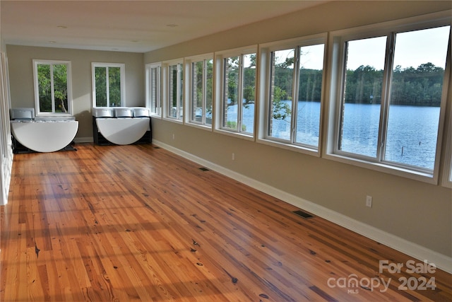 unfurnished sunroom with a water view and a wealth of natural light