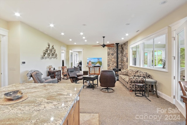 carpeted living room with ceiling fan and a wood stove