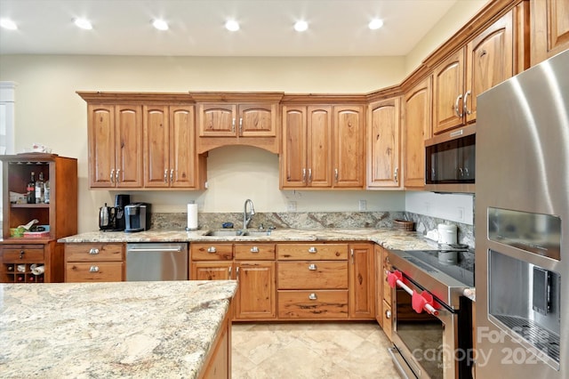 kitchen with light stone countertops, sink, and appliances with stainless steel finishes