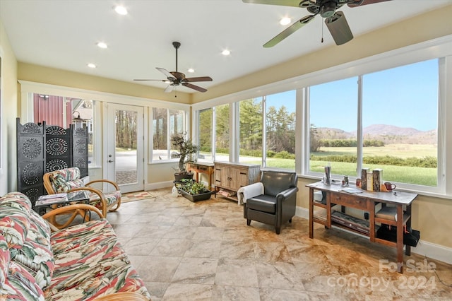 sunroom / solarium with a mountain view, plenty of natural light, and ceiling fan