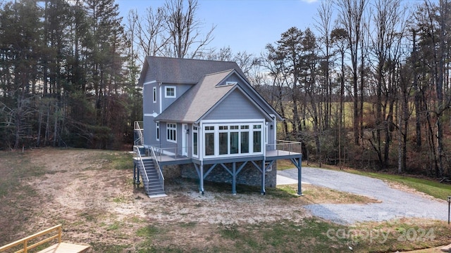 rear view of house featuring a wooden deck, a sunroom, and cooling unit