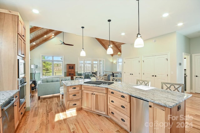 kitchen featuring beam ceiling, ceiling fan, stainless steel appliances, a breakfast bar, and light wood-type flooring