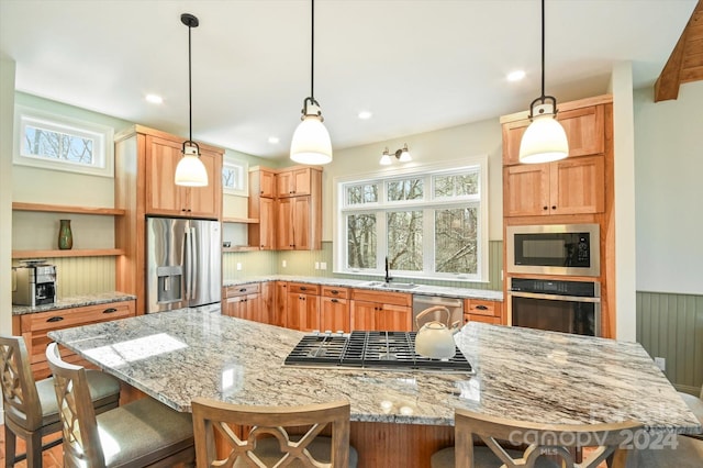 kitchen featuring light stone countertops, appliances with stainless steel finishes, hanging light fixtures, and a kitchen breakfast bar