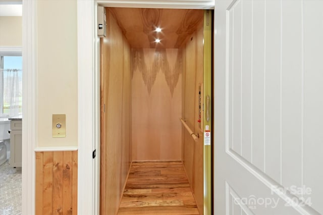 interior space featuring hardwood / wood-style floors, wood walls, and elevator