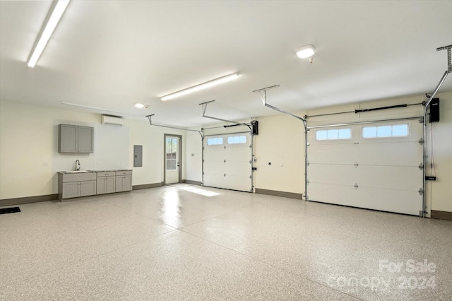 garage featuring a wall unit AC, electric panel, and sink