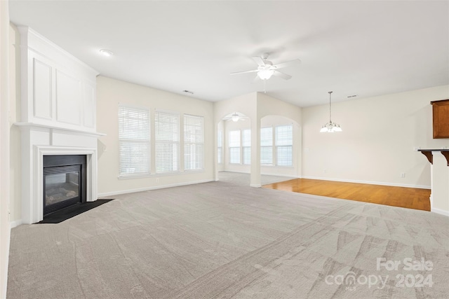 unfurnished living room with ceiling fan with notable chandelier and light wood-type flooring