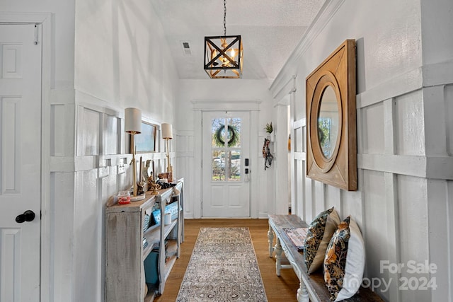 entrance foyer featuring wood-type flooring, a textured ceiling, lofted ceiling, and a notable chandelier