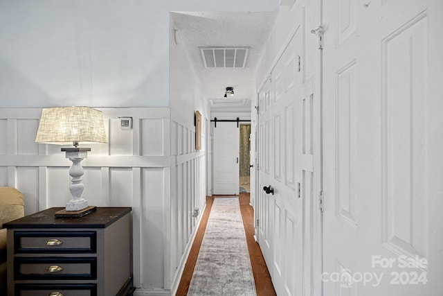 hallway with dark hardwood / wood-style floors, a barn door, and a textured ceiling