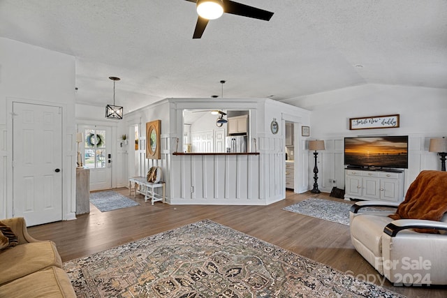 living room with a textured ceiling, ceiling fan, wood-type flooring, and lofted ceiling