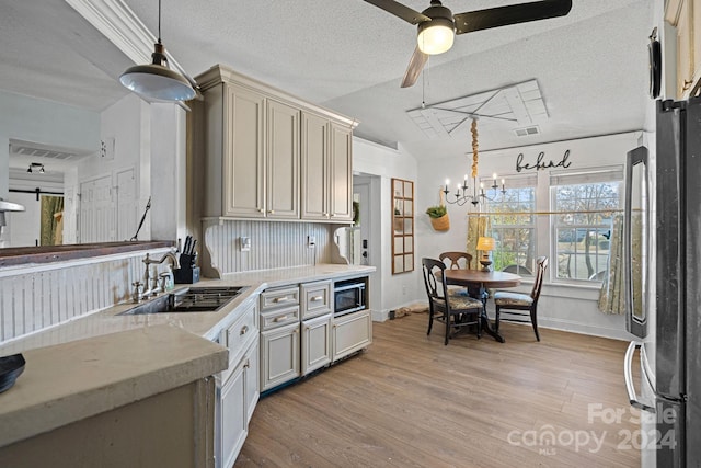 kitchen with a textured ceiling, light wood-type flooring, hanging light fixtures, and sink