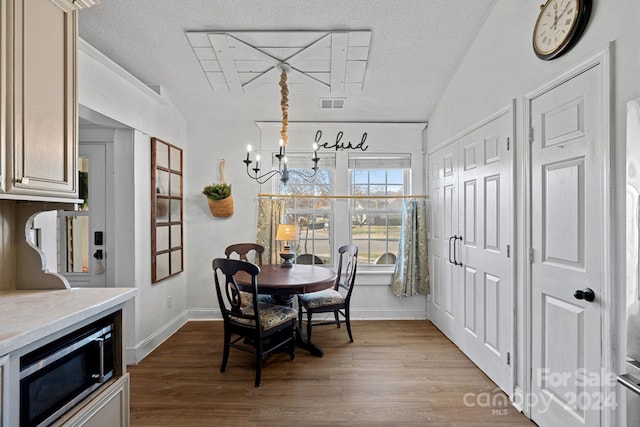 dining room with a textured ceiling, light hardwood / wood-style floors, and vaulted ceiling