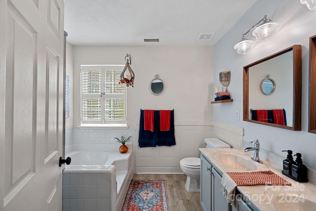 bathroom with tile patterned floors, vanity, a relaxing tiled tub, and toilet