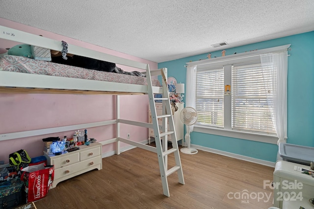 bedroom with hardwood / wood-style floors and a textured ceiling