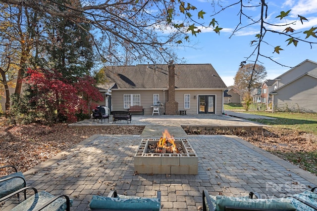 rear view of property with a fire pit and a patio