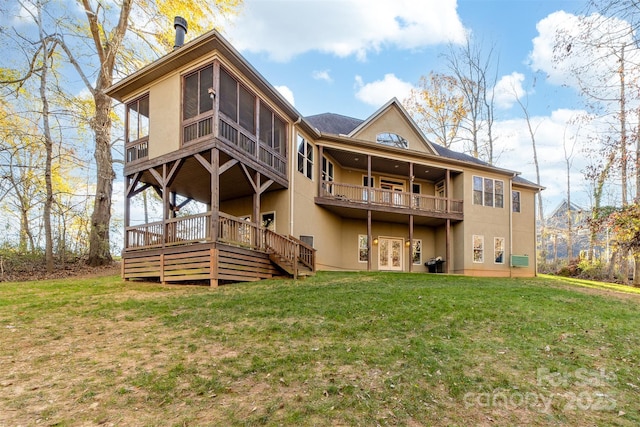 back of property with a yard, a sunroom, and a deck