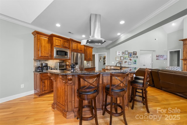 kitchen with appliances with stainless steel finishes, a kitchen breakfast bar, island exhaust hood, ornamental molding, and a center island