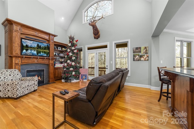 living room with french doors, crown molding, high vaulted ceiling, and light hardwood / wood-style flooring