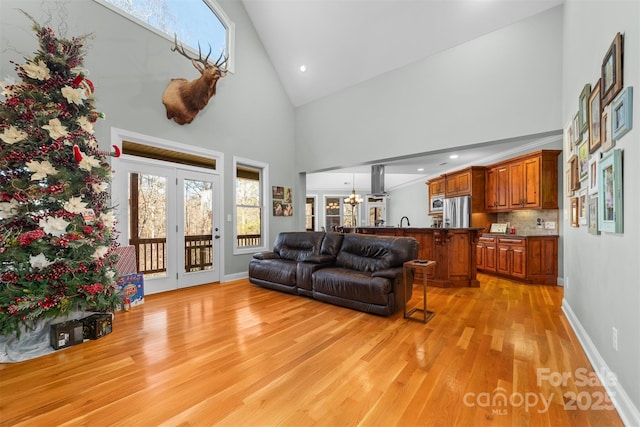 living room featuring a chandelier, high vaulted ceiling, and light hardwood / wood-style flooring